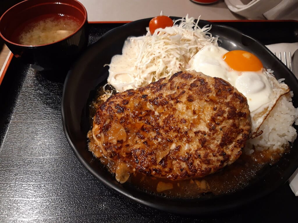 ハンバーグ細切りレタス目玉焼きご飯を盛った皿と脇に味噌汁の椀を載せたトレー 立川駅徒歩1分年中無休の溶岩ホットヨガスタジオ