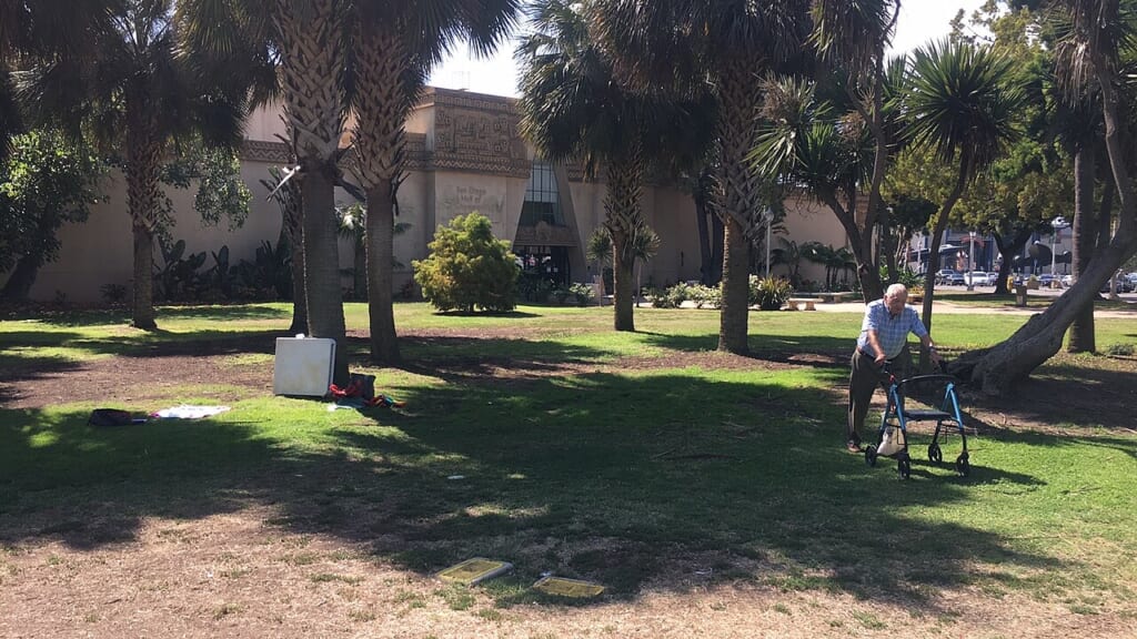 Balboa Park San Diego CA USA Near Future Comic Con Museum man with walker | オンザショア立川店 立川駅徒歩1分年中無休の溶岩ホットヨガスタジオ 建物の前で歩行器を両手で支えながら屋外を歩いている男性の姿 立川駅徒歩1分年中無休の溶岩ホットヨガスタジオ