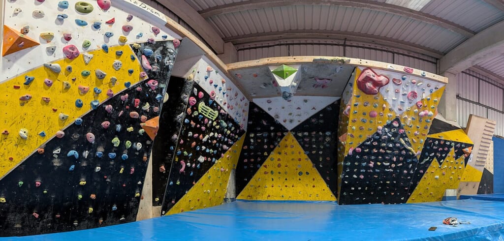 Gorliz sports center climbing gym | オンザショア立川店 立川駅徒歩1分年中無休の溶岩ホットヨガスタジオ 角度の異なる複数の壁と小さな張り出しがあり床に厚い青色のマットを敷いた室内クライミング施設 立川駅徒歩1分年中無休の溶岩ホットヨガスタジオ