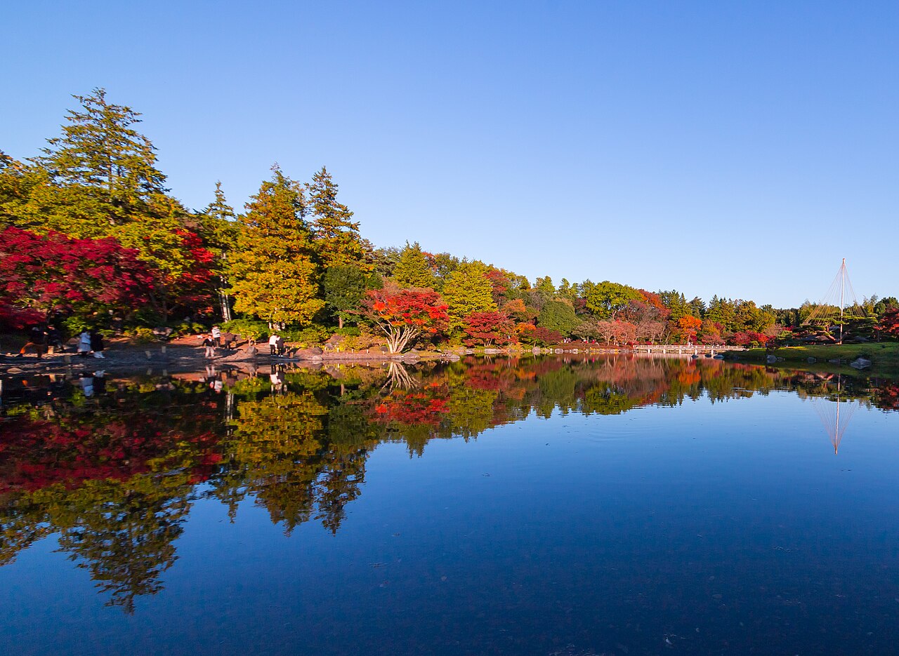 Autumn in Showa Kinen Park's Japanese Garden, with red and gold trees reflected in the pond