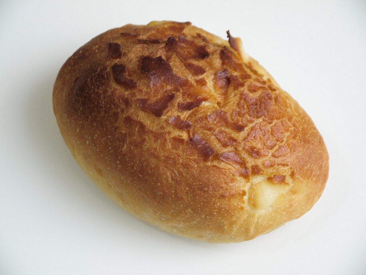 白い台の上に置かれた、表面に焼き色の模様がついた楕円形のパン1個