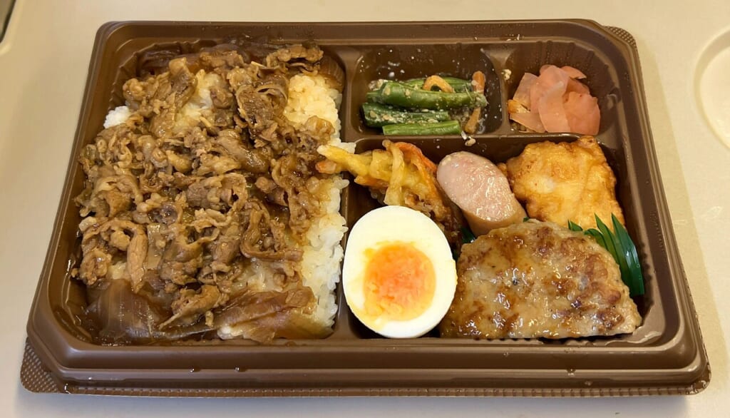 ご飯と牛肉のおかずなどを一つの容器に詰め合わせた幕の内弁当の写真 立川駅徒歩1分年中無休の溶岩ホットヨガスタジオ