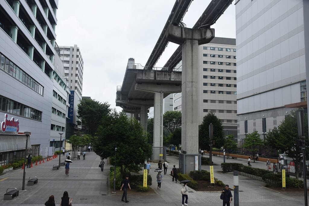 Sun Sun Road Cinema Two and Tama Monorail in Tachikawa 20260717 | オンザショア立川店 立川駅徒歩1分年中無休の溶岩ホットヨガスタジオ サンサンロードの歩行者道左にシネマツー上に多摩モノレールの高架が通る 立川駅徒歩1分年中無休の溶岩ホットヨガスタジオ