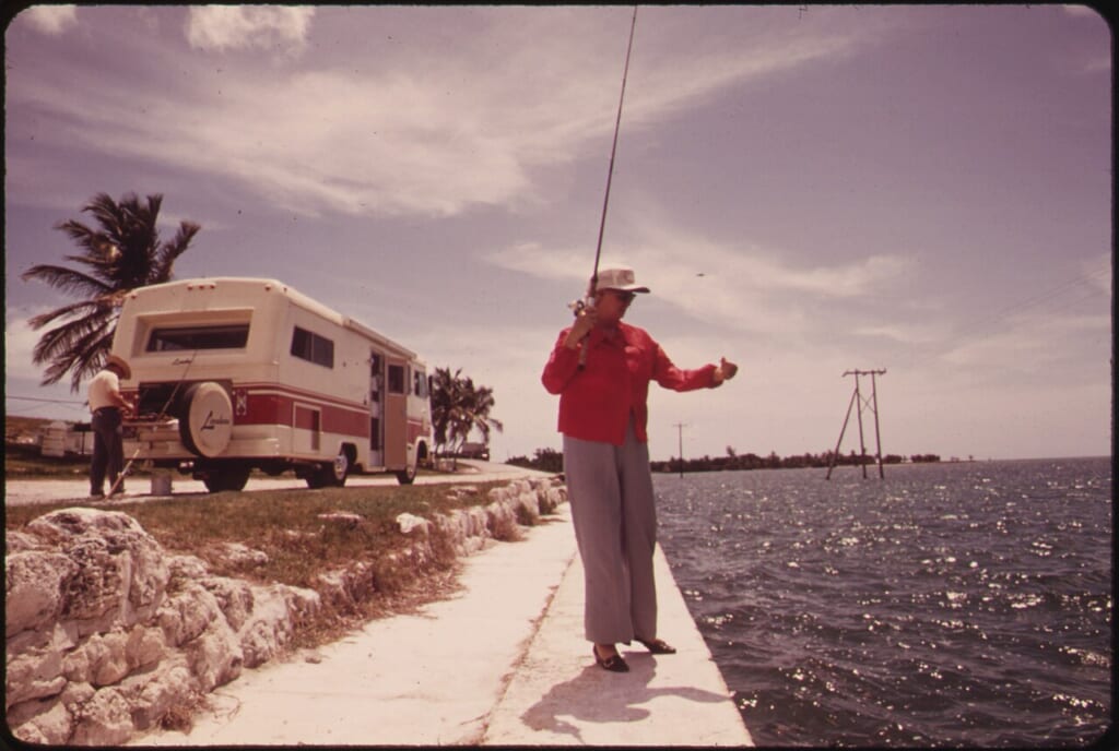 A RETIRED COUPLE FROM CALIFORNIA STOP TO FISH OFF EMBANKMENT AT SPANISH HARBOR KEY TRAVELTRAILERS OF THE KIND OWNED NARA 548743 | オンザショア立川店 立川駅徒歩1分年中無休の溶岩ホットヨガスタジオ 水辺の堤防から釣りをする二人とその周囲に広がる水面の風景を写した写真 立川駅徒歩1分年中無休の溶岩ホットヨガスタジオ