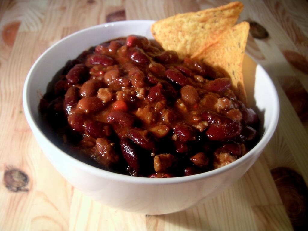 Bowl of chili | オンザショア立川店 立川駅徒歩1分年中無休の溶岩ホットヨガスタジオ 肉や豆トマト唐辛子を使ったチリコンカンに2枚のトルティーヤチップスを添えた一皿 立川駅徒歩1分年中無休の溶岩ホットヨガスタジオ