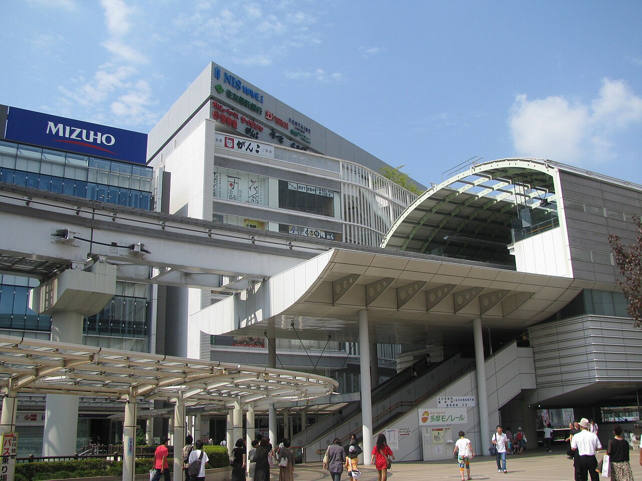 多摩モノレールの立川北駅。高架の駅舎と、その下の歩道を行き交う人びと