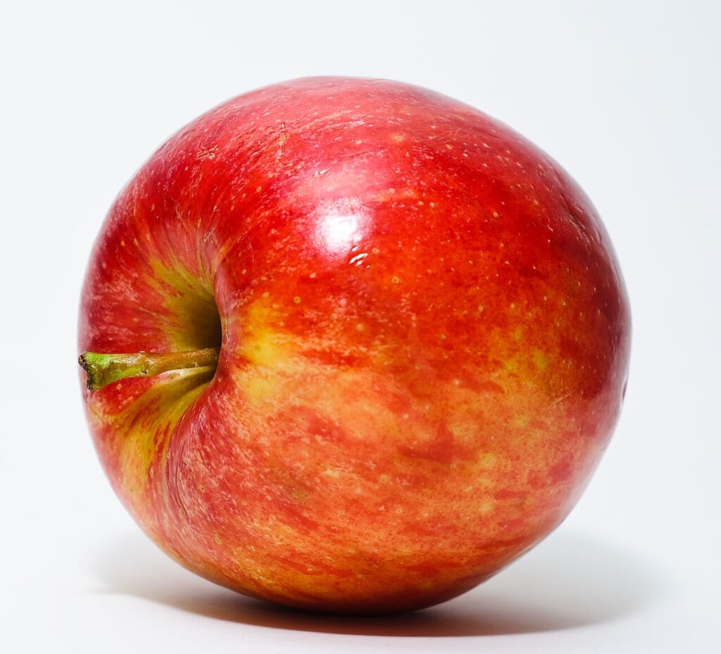 Red Apple | オンザショア立川店 立川駅徒歩1分年中無休の溶岩ホットヨガスタジオ 白い背景の前に置かれた赤い皮の丸ごとのりんごを写した写真 立川駅徒歩1分年中無休の溶岩ホットヨガスタジオ