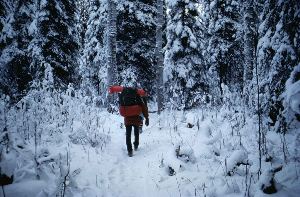 Man with backpacking walking in forest at winter | オンザショア立川店 立川駅徒歩1分年中無休の溶岩ホットヨガスタジオ 冬の森の中でバックパックを背負いながら歩いている男性の姿を写した写真 立川駅徒歩1分年中無休の溶岩ホットヨガスタジオ
