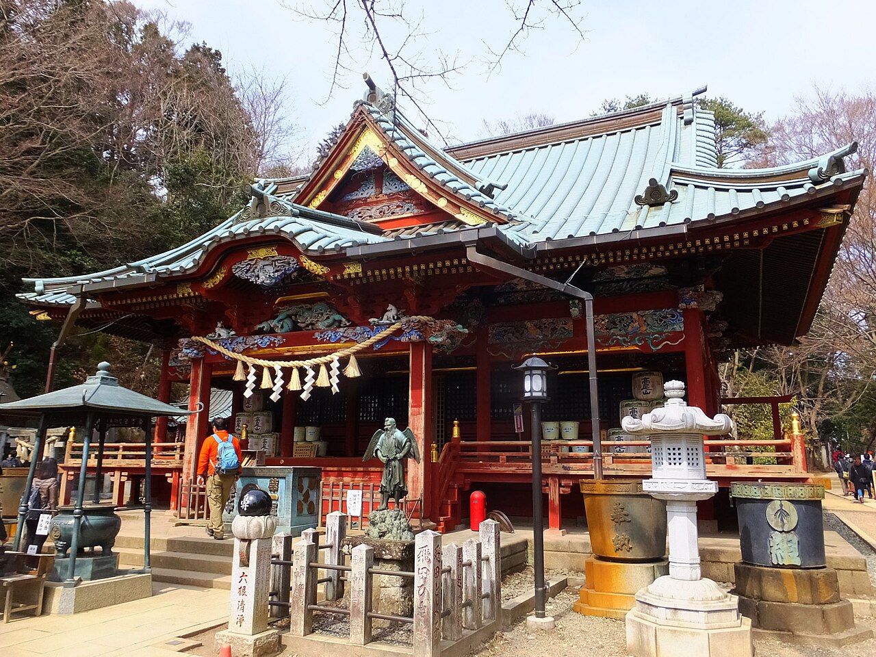 The Izuna Gongen hall of Takaosan Yakuo-in, richly carved and painted, with stone lanterns in front.