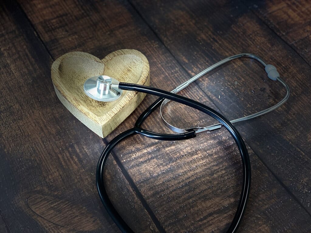 Health Health Stethoscope 50191694581 | オンザショア立川店 立川駅徒歩1分年中無休の溶岩ホットヨガスタジオ 木目の背景に置かれた聴診器と木製のハート形のオブジェを写した写真 立川駅徒歩1分年中無休の溶岩ホットヨガスタジオ