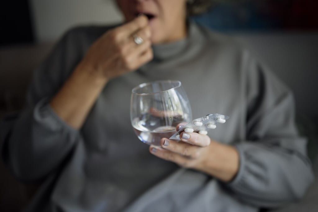 片方の手に錠剤を持ちもう片方の手で水の入ったコップを持っている様子 立川駅徒歩1分年中無休の溶岩ホットヨガスタジオ