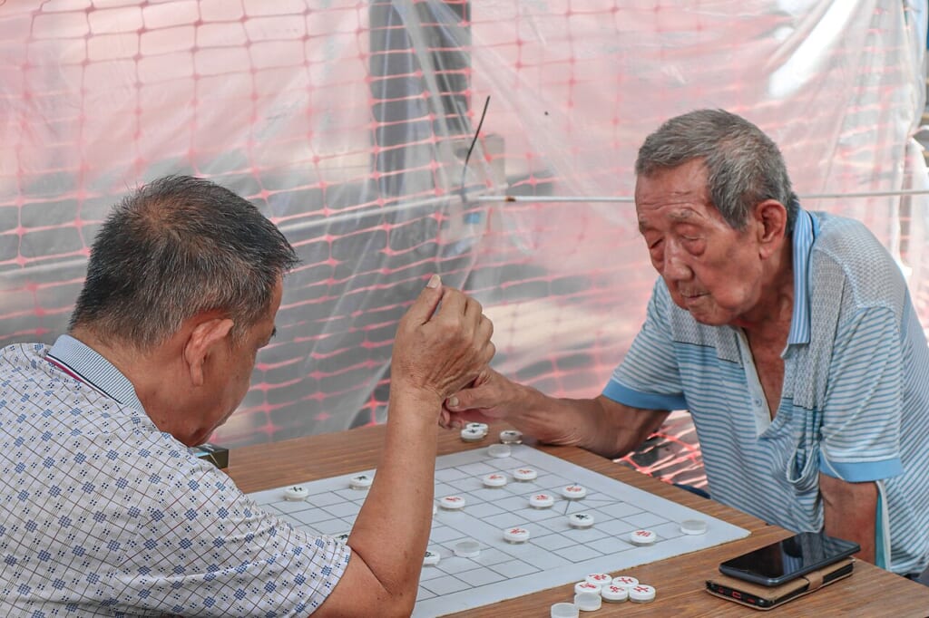 Chess game with mates | オンザショア立川店 立川駅徒歩1分年中無休の溶岩ホットヨガスタジオ 中国将棋の盤を挟んで向かい合い二人が一緒に対局をしている様子 立川駅徒歩1分年中無休の溶岩ホットヨガスタジオ