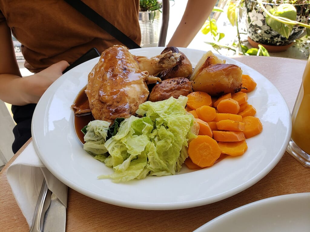 Roast Chicken Kitchen Cafe 20230610 | オンザショア立川店 立川駅徒歩1分年中無休の溶岩ホットヨガスタジオ ローストチキンににんじんとキャベツを添えて白い皿に盛った一皿 立川駅徒歩1分年中無休の溶岩ホットヨガスタジオ