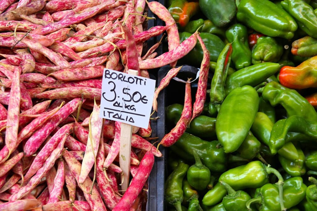 28 Borlotti bean variety food prices at grocery market in Italy | オンザショア立川店 立川駅徒歩1分年中無休の溶岩ホットヨガスタジオ 市場の売り場に並べられたボルロッティ豆と緑色のフリッジテッロ唐辛子 立川駅徒歩1分年中無休の溶岩ホットヨガスタジオ