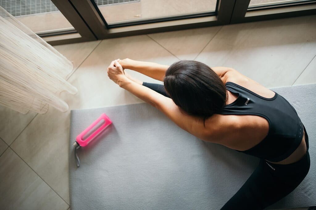 Top view of a woman stretching on a yoga mat | オンザショア立川店 立川駅徒歩1分年中無休の溶岩ホットヨガスタジオ ヨガマットの上でストレッチをしている女性の姿を上から写した写真 立川駅徒歩1分年中無休の溶岩ホットヨガスタジオ