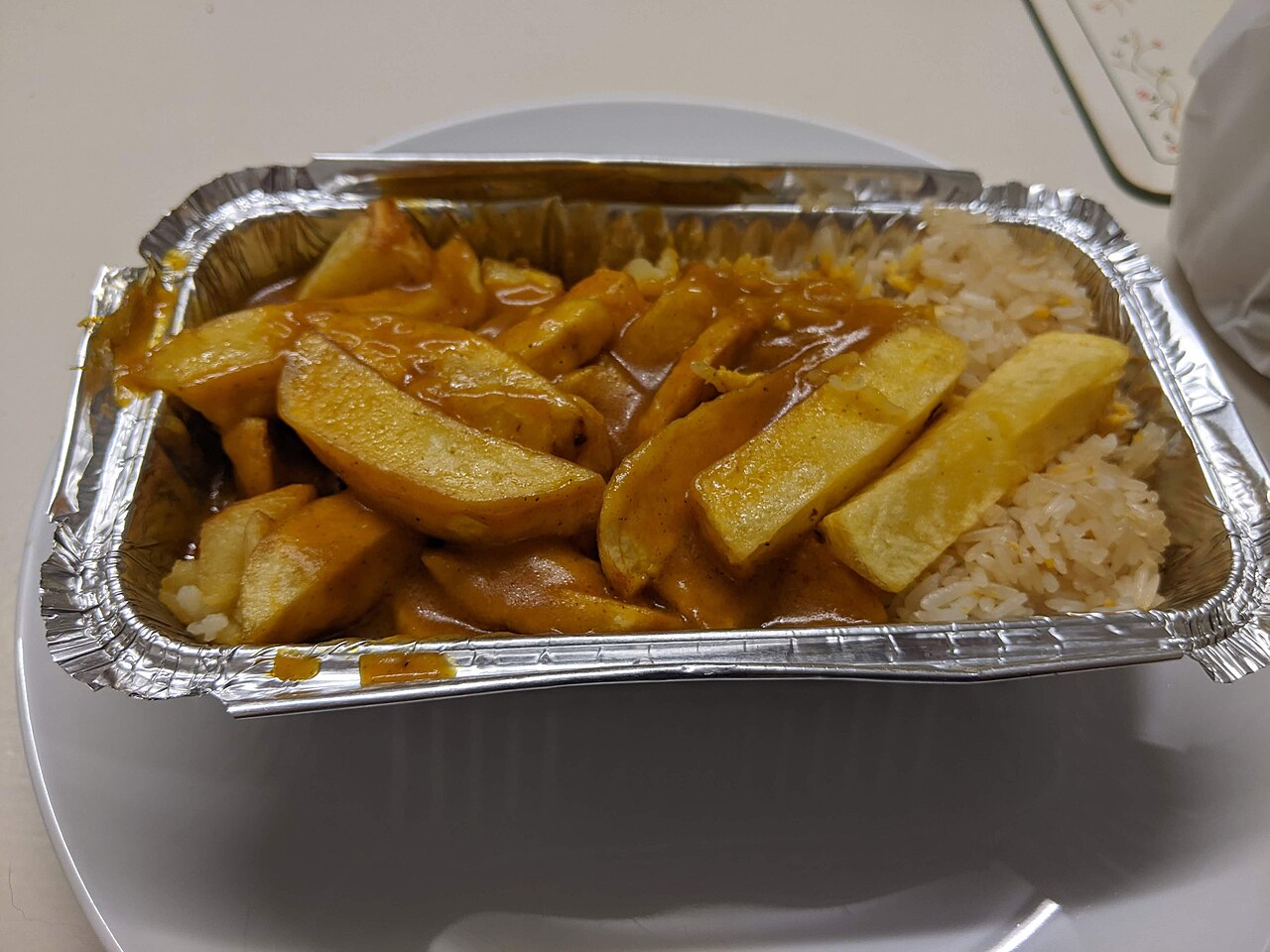 皿の上に置かれたアルミ製のトレーに盛り付けられたファストフードの料理。