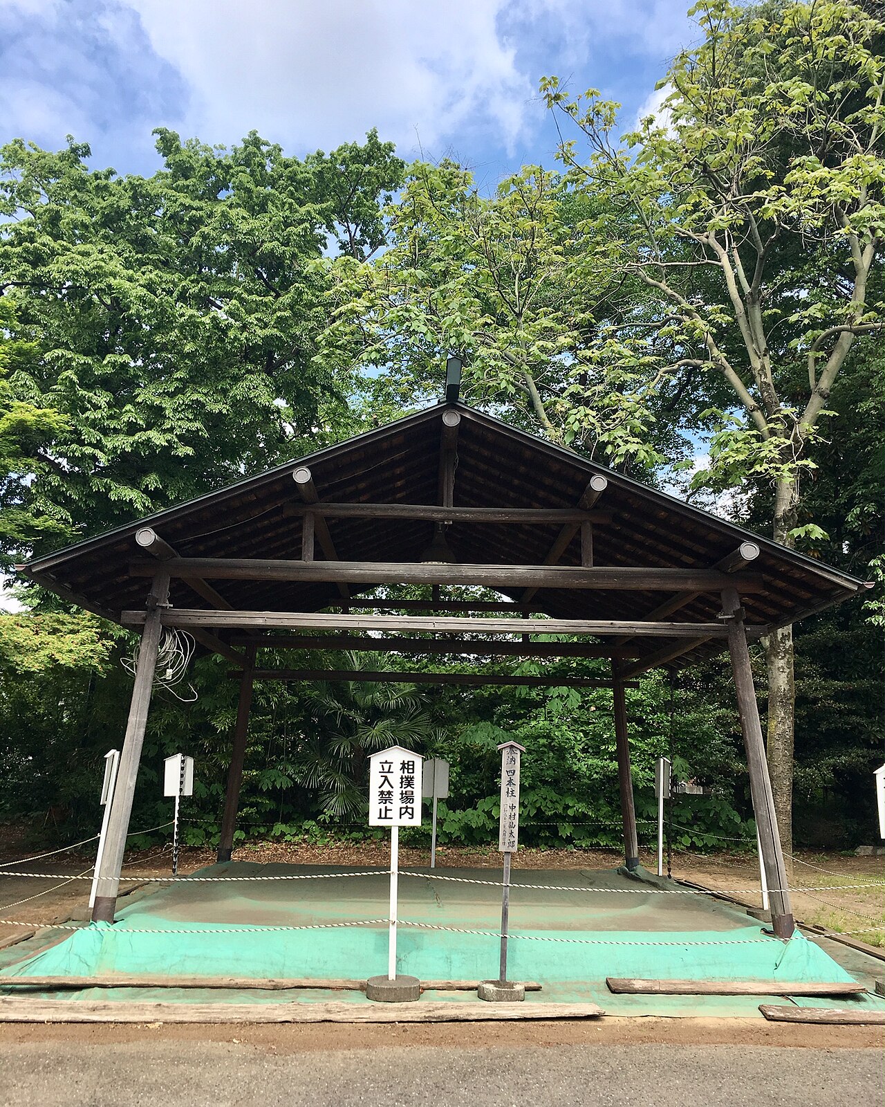 諏訪神社の境内にある土俵。屋根のかかった土俵を、新緑の木々が囲んでいる。