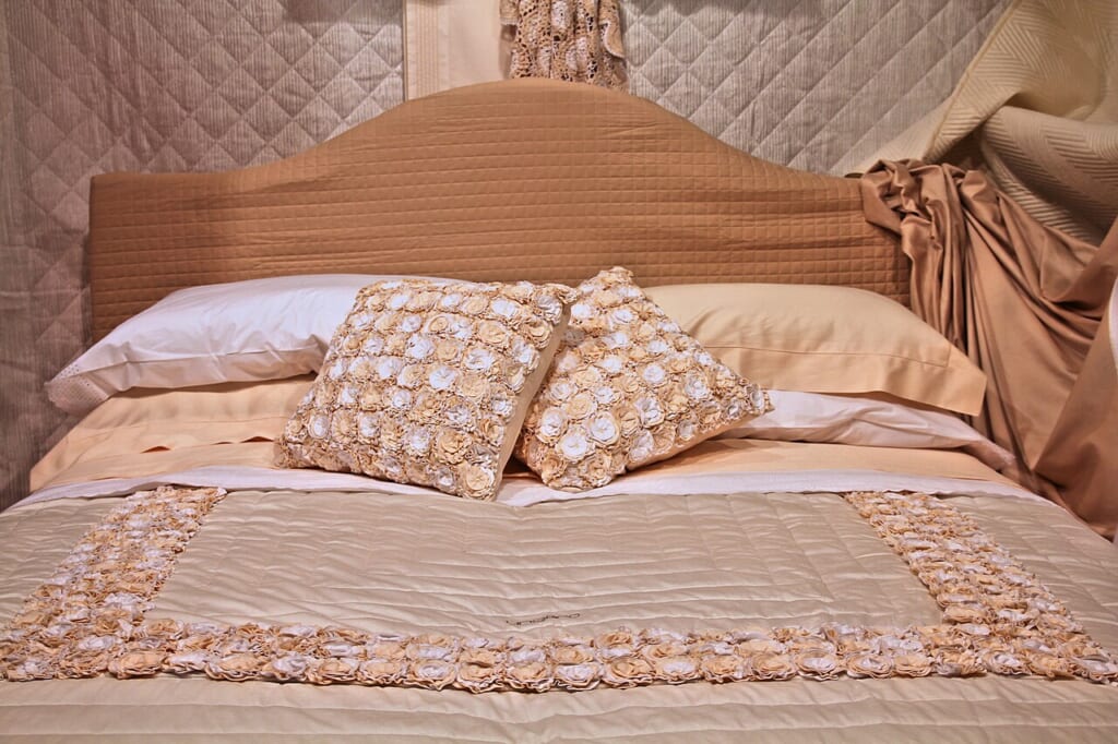 44 Made bed with richly decorated pillows and ornate bedspread | オンザショア立川店 立川駅徒歩1分年中無休の溶岩ホットヨガスタジオ 装飾のある枕とベッドカバーが整えられたベージュを基調とする寝室のダブルベッド 立川駅徒歩1分年中無休の溶岩ホットヨガスタジオ