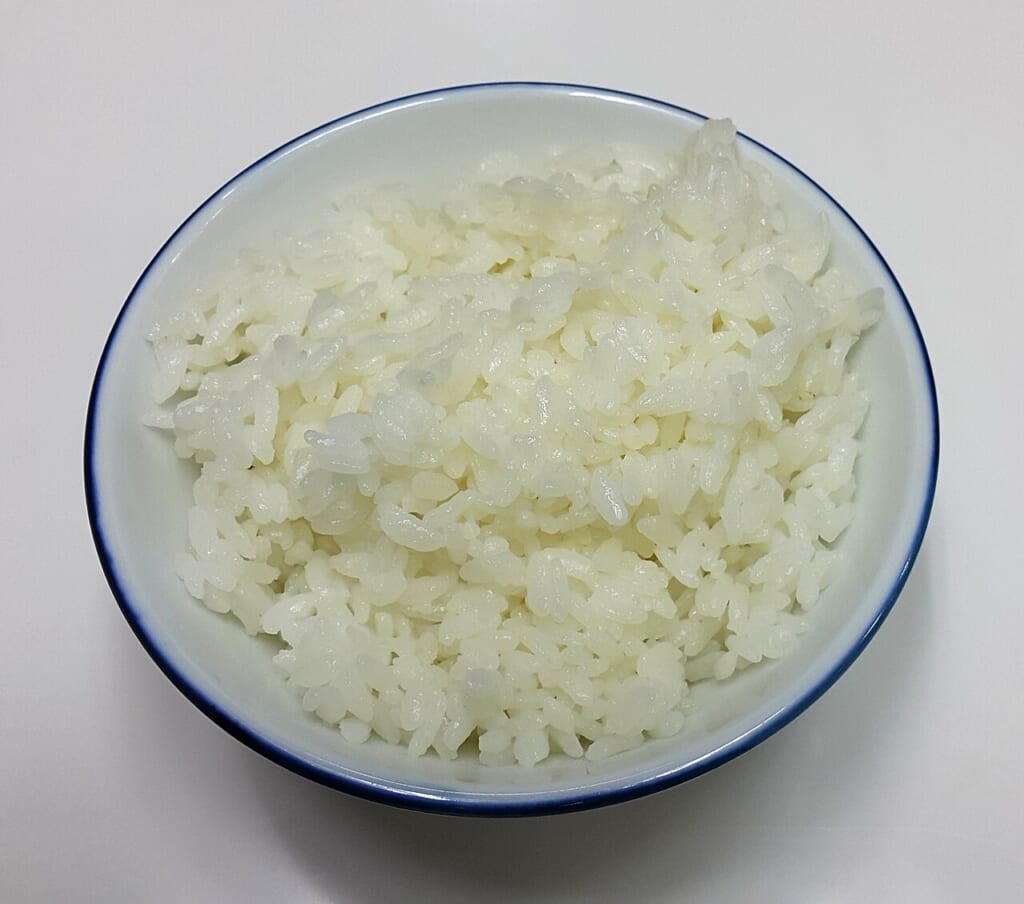 白いテーブルの上に置かれた青い縁取りのある白い茶碗に盛られた白いご飯 立川駅徒歩1分年中無休の溶岩ホットヨガスタジオ