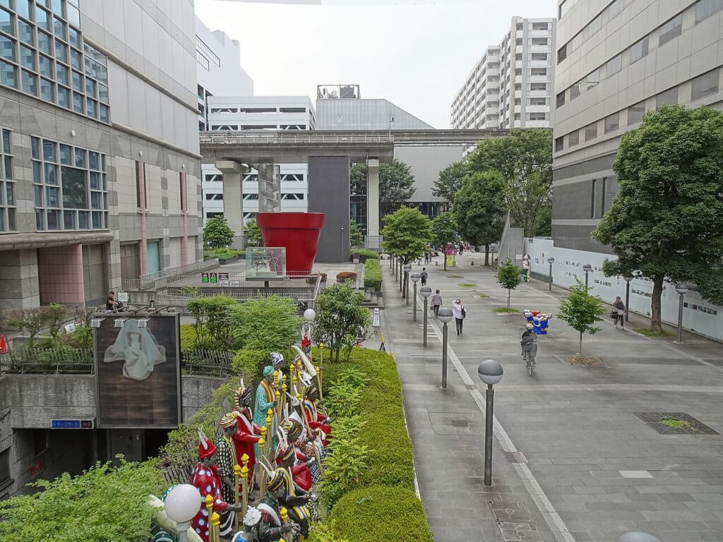 上から見たファーレ立川の歩行者道赤い大きな植木鉢の向こうをモノレールが渡る 立川駅徒歩1分年中無休の溶岩ホットヨガスタジオ
