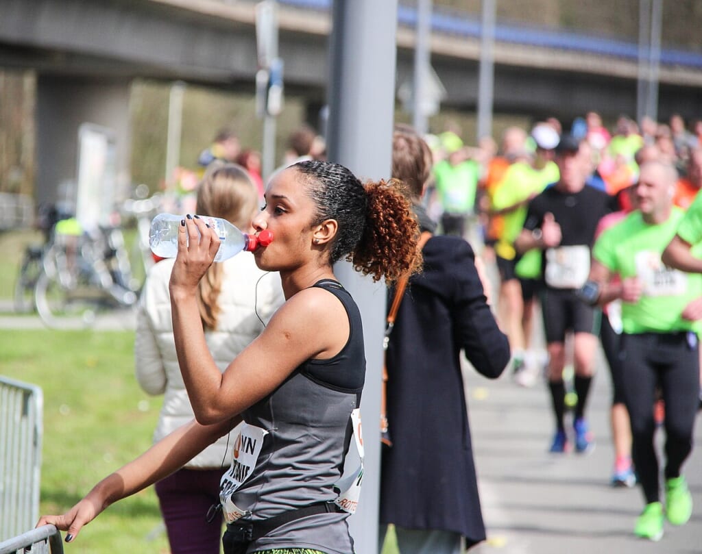 Standing drinking sportswoman during Marathon Rotterdam 2015 | オンザショア立川店 立川駅徒歩1分年中無休の溶岩ホットヨガスタジオ マラソンの途中で立ち止まり飲み物を口にしているランナーの様子 立川駅徒歩1分年中無休の溶岩ホットヨガスタジオ