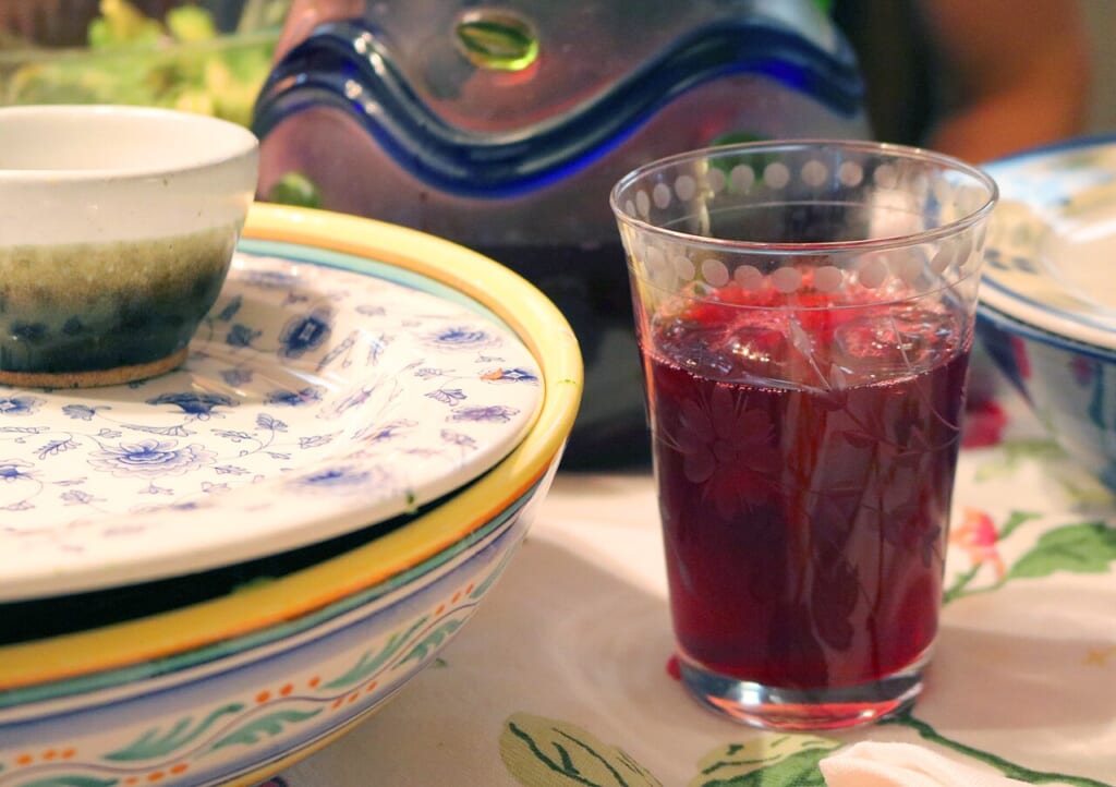 A glass of hibiscus tea 02 | オンザショア立川店 立川駅徒歩1分年中無休の溶岩ホットヨガスタジオ テーブルの上に置かれたグラスに入ったハイビスカスティーの写真 立川駅徒歩1分年中無休の溶岩ホットヨガスタジオ