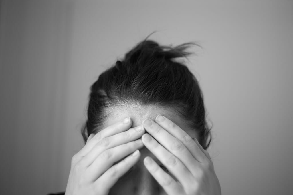 Headache touching forehead | オンザショア立川店 立川駅徒歩1分年中無休の溶岩ホットヨガスタジオ 額に手を当てている人物の様子を横長の画面に収めた頭痛を題材とする写真 立川駅徒歩1分年中無休の溶岩ホットヨガスタジオ