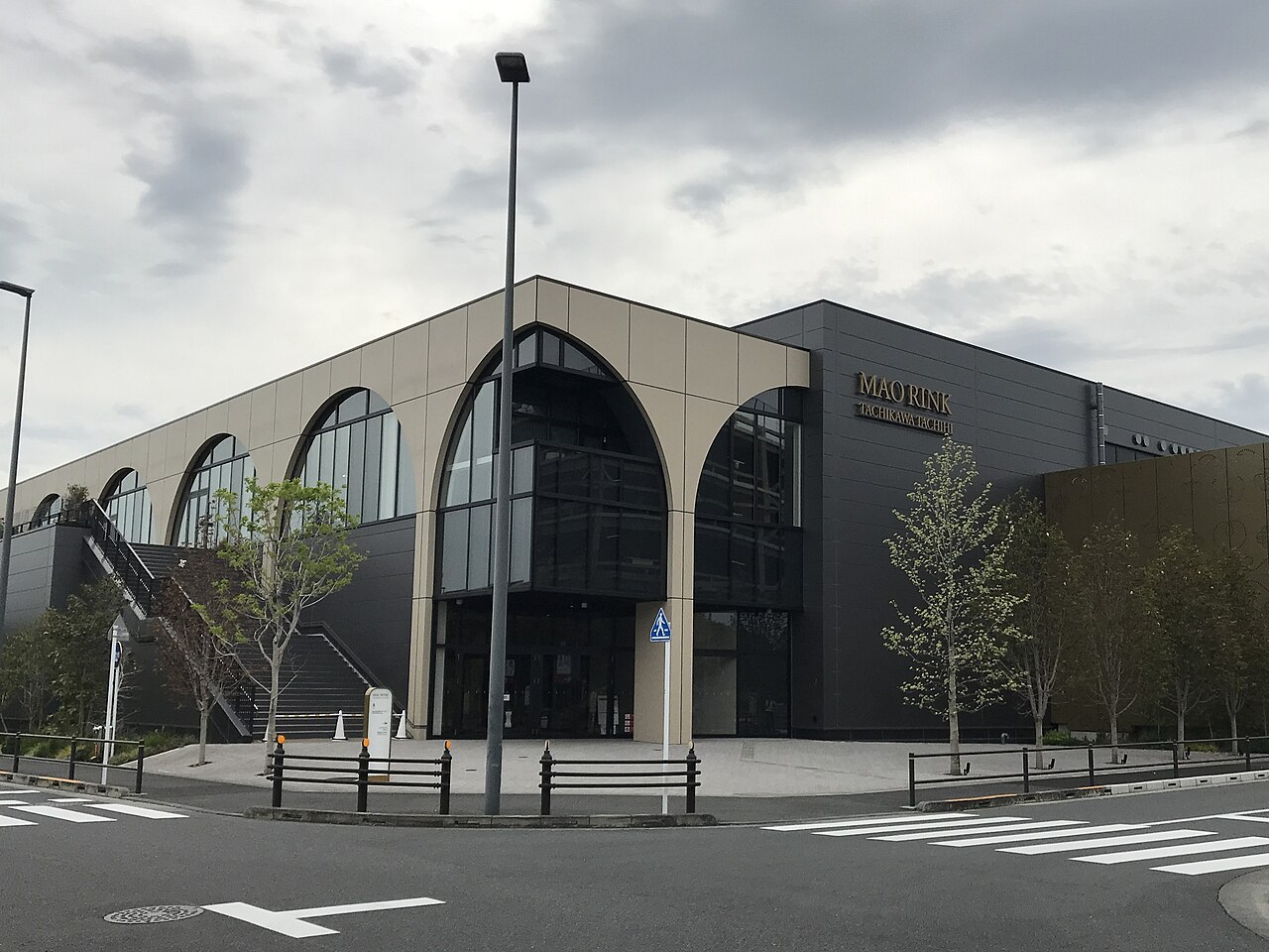 The exterior of MAO RINK TACHIKAWA TACHIHI, a building lined with large arched windows (2025)