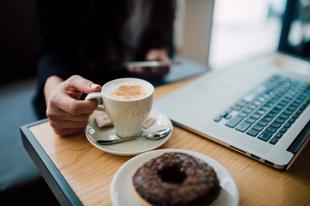 Closeup of a woman using her smartphone while having coffee | オンザショア立川店 立川駅徒歩1分年中無休の溶岩ホットヨガスタジオ コーヒーを飲みながらスマートフォンを使う女性を近くから撮影した写真 立川駅徒歩1分年中無休の溶岩ホットヨガスタジオ