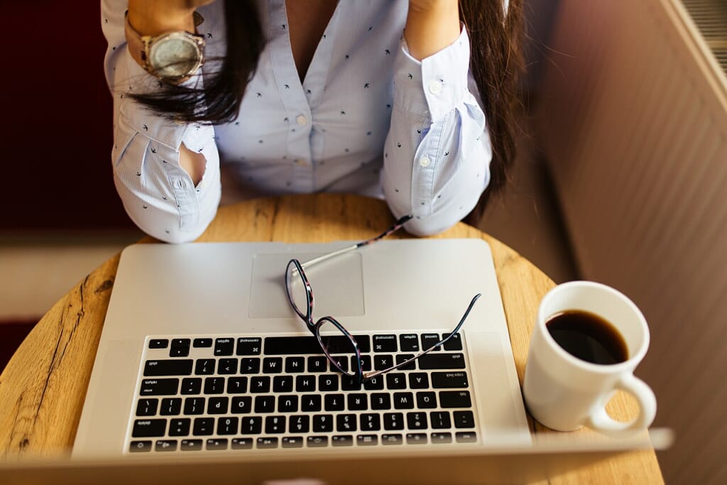 自宅でノートパソコンとコーヒーを前にして疲れた様子を見せる女性 立川駅徒歩1分年中無休の溶岩ホットヨガスタジオ
