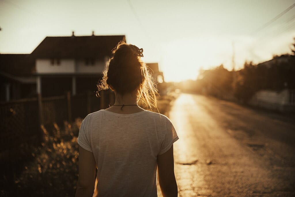 Woman walking down the street in the sunset | オンザショア立川店 立川駅徒歩1分年中無休の溶岩ホットヨガスタジオ 夕暮れの街路を歩く女性の姿を捉えた屋外での日常的な歩行風景の写真 立川駅徒歩1分年中無休の溶岩ホットヨガスタジオ