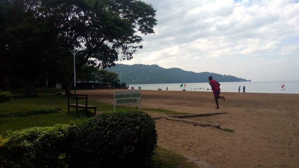 A young man jogging on Lake Kivu public beach | オンザショア立川店 立川駅徒歩1分年中無休の溶岩ホットヨガスタジオ 湖畔のビーチでジョギングをする男性屋外で走る様子を捉えた写真 立川駅徒歩1分年中無休の溶岩ホットヨガスタジオ