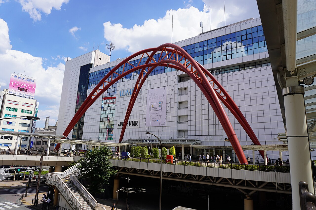 The North Exit of JR Tachikawa Station, with a red arch and the elevated pedestrian deck (taken 2021)