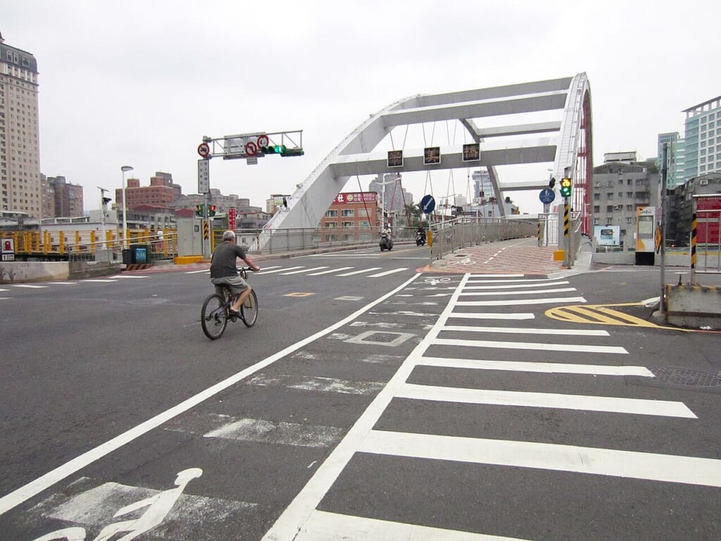 景美橋の方向へ向かって自転車をこぐ男性の姿を収めた屋外での写真 立川駅徒歩1分年中無休の溶岩ホットヨガスタジオ