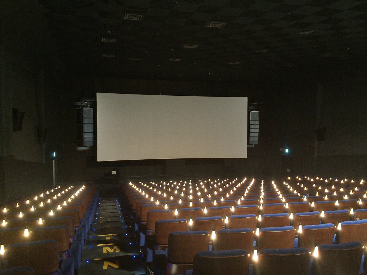 Seats and screen of Cinema Two's a studio, with small lights glowing between the seats