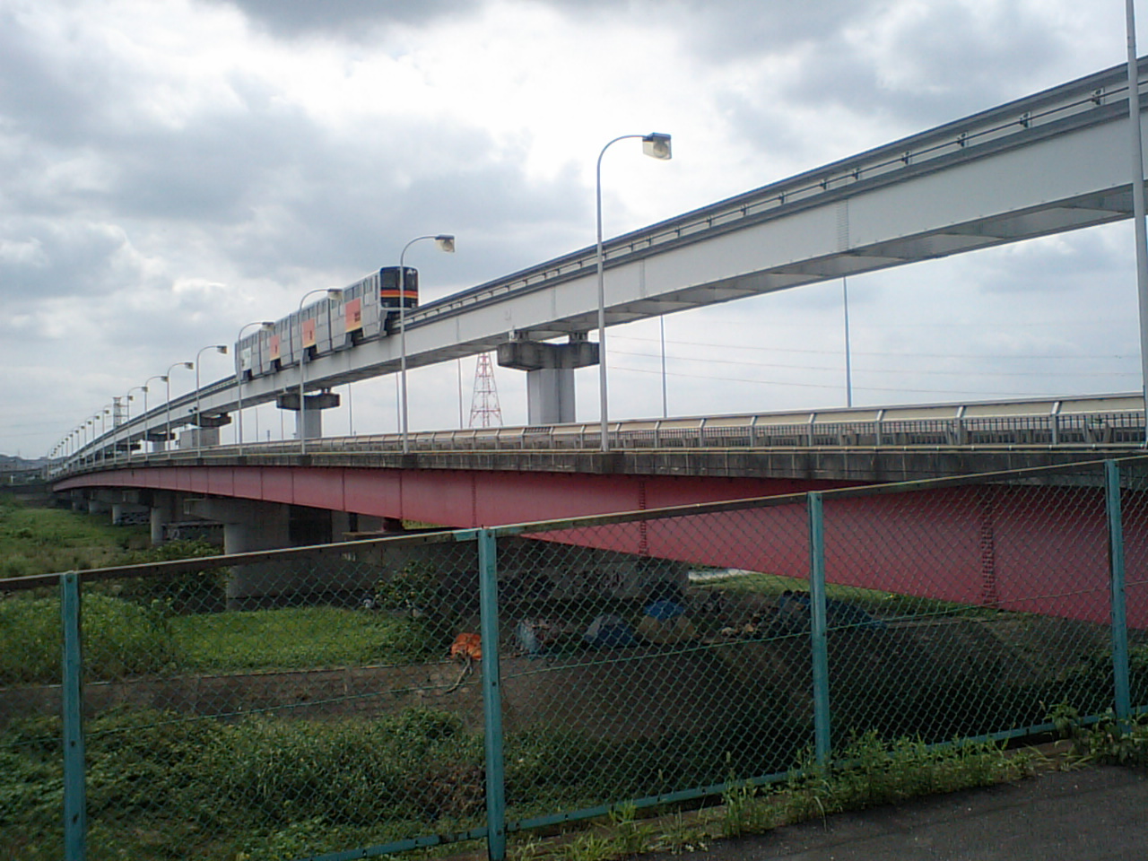 The Tachihi Bridge over the Tama River, the monorail guideway crossing above the red-girdered road deck