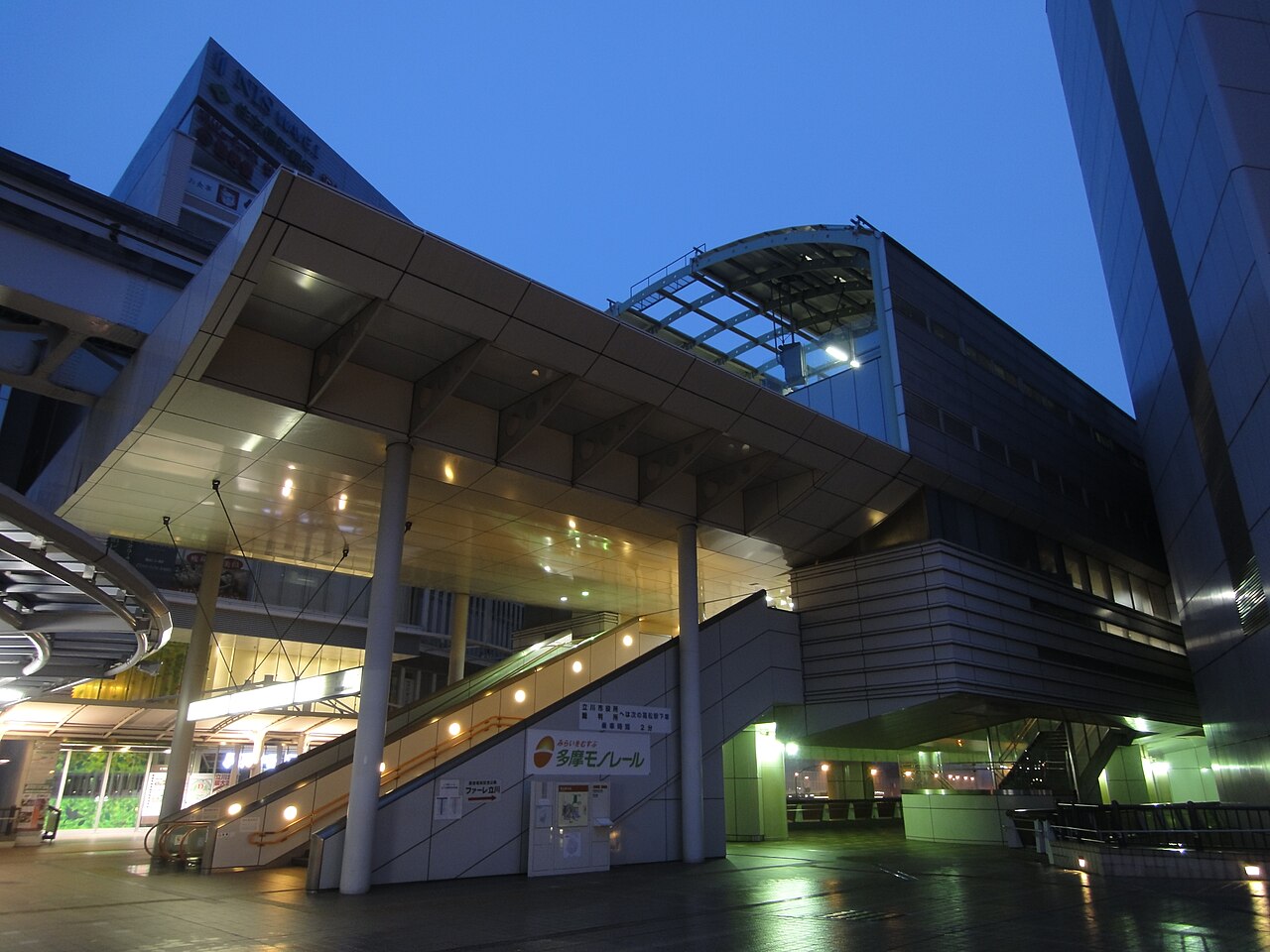 Tachikawa-Kita Station at dusk, stairs and escalators rising to the lit station building