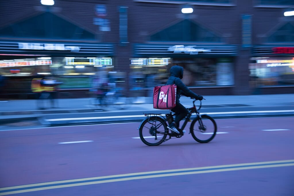 ニューヨーク市で食事の配達を担う配達員の姿を写した街中の写真 立川駅徒歩1分年中無休の溶岩ホットヨガスタジオ