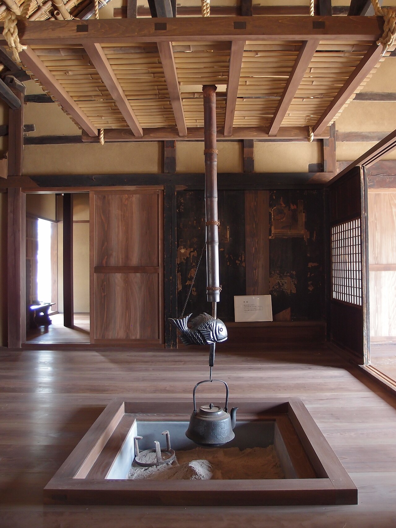 Inside an old farmhouse at Komorebi Village: a hearth with a pot hook and iron kettle
