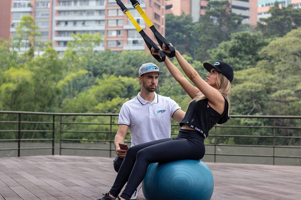 Personal training TRX rows 2 | オンザショア立川店 立川駅徒歩1分年中無休の溶岩ホットヨガスタジオ ジムで吊り下げ式のストラップを使い指導者とともに体を動かす人 立川駅徒歩1分年中無休の溶岩ホットヨガスタジオ