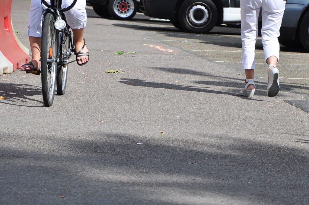 フランスの歩道で自転車をこぐ女性と歩く女性の足元を写した写真 立川駅徒歩1分年中無休の溶岩ホットヨガスタジオ
