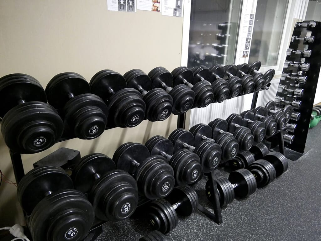 Dumbbells on rack 20180112 | オンザショア立川店 立川駅徒歩1分年中無休の溶岩ホットヨガスタジオ ラックの上に並べて置かれた筋力トレーニングに用いるダンベル 立川駅徒歩1分年中無休の溶岩ホットヨガスタジオ