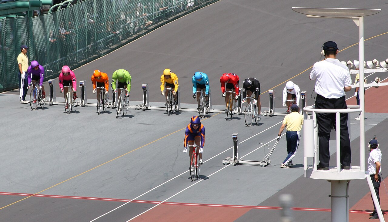 The track at Tachikawa Keirin, with riders in colourful racing silks lined up at the start