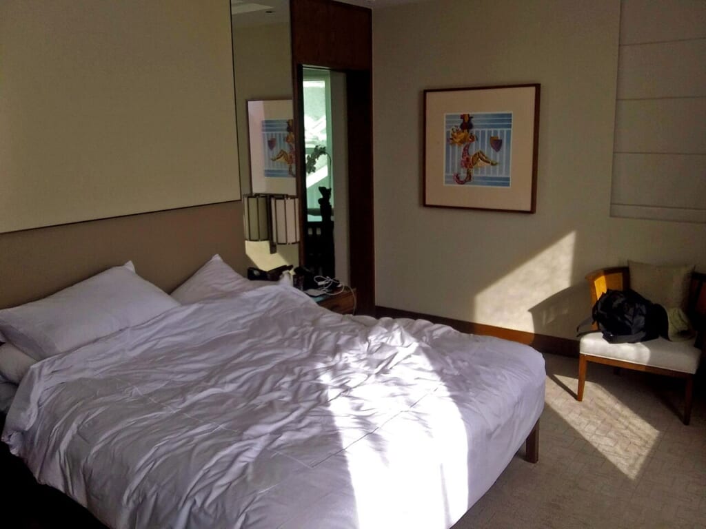 Bedroom in suite at Conrad Centennial Singapore | オンザショア立川店 立川駅徒歩1分年中無休の溶岩ホットヨガスタジオ 室内に置かれたベッドを写した寝室の写真眠るための寝床が室内に見える 立川駅徒歩1分年中無休の溶岩ホットヨガスタジオ