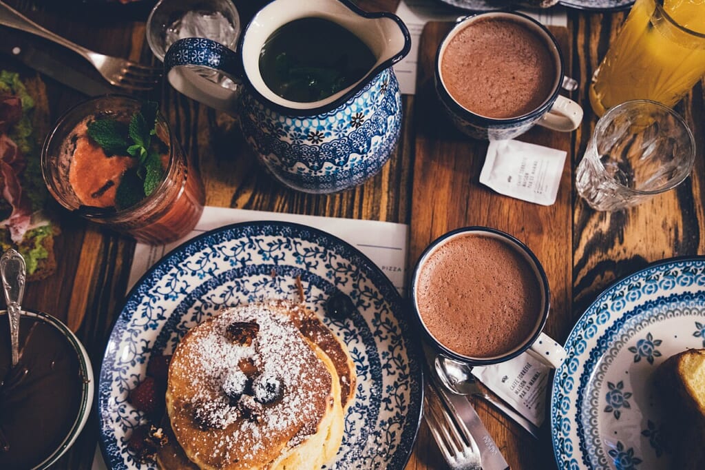 Breakfast table with pancakes Unsplash | オンザショア立川店 立川駅徒歩1分年中無休の溶岩ホットヨガスタジオ パンケーキを盛った皿をはじめ朝食の料理が卓上に並べられている 立川駅徒歩1分年中無休の溶岩ホットヨガスタジオ