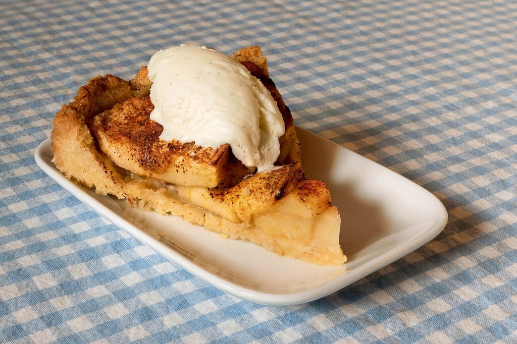 Apple cake with vanilla ice cream 2 | オンザショア立川店 立川駅徒歩1分年中無休の溶岩ホットヨガスタジオ チェック柄のテーブルクロスの上でバニラアイスクリームを添えたアップルパイ 立川駅徒歩1分年中無休の溶岩ホットヨガスタジオ