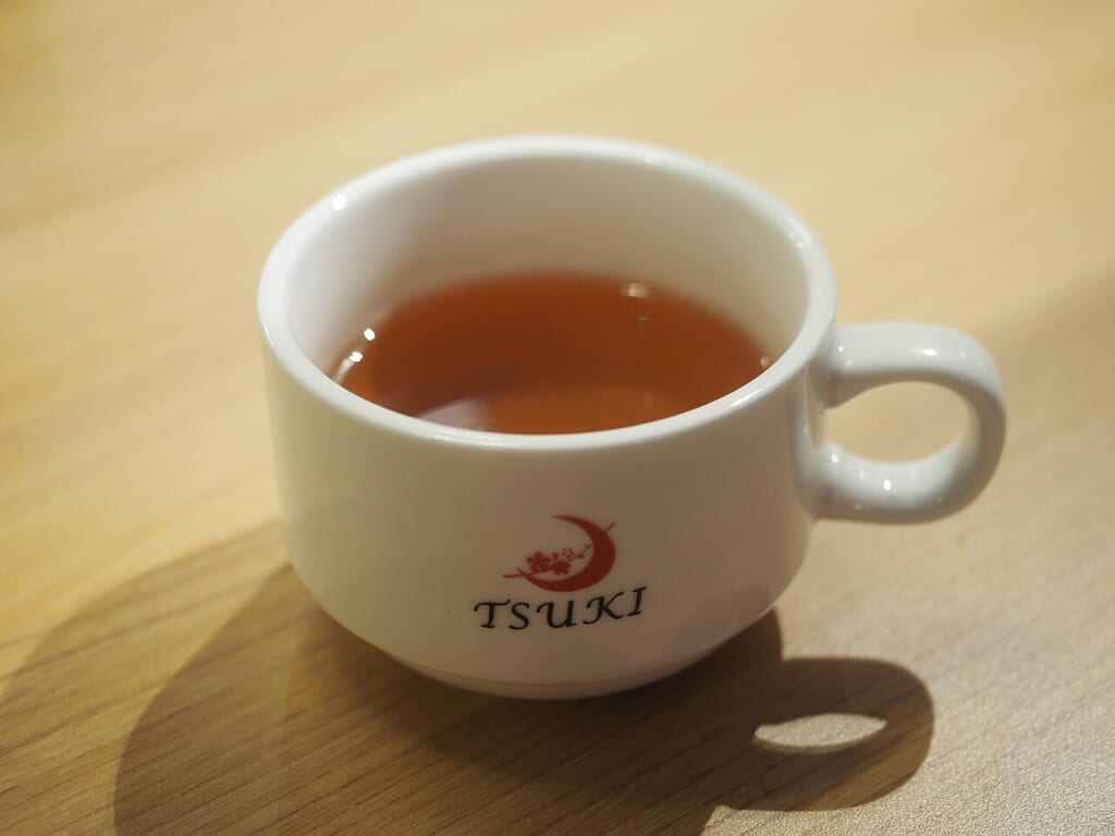 Cup of green tea at restaurant Tsuki | オンザショア立川店 立川駅徒歩1分年中無休の溶岩ホットヨガスタジオ カップに入った緑茶を写した写真緑茶と飲用のカップが画面に収められている 立川駅徒歩1分年中無休の溶岩ホットヨガスタジオ