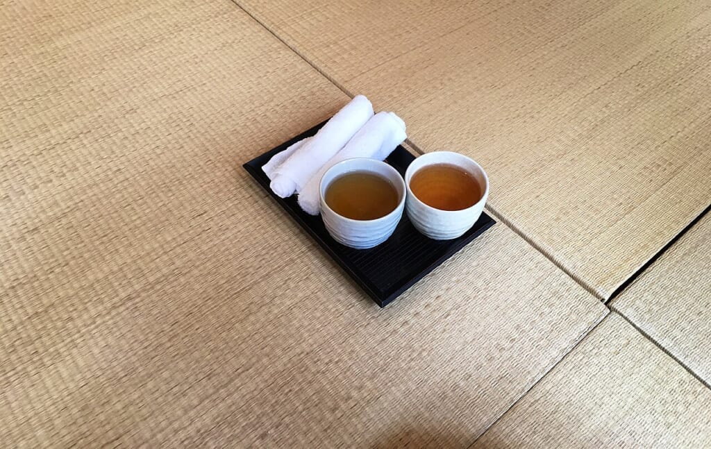Tea at Shanti Yoga Vegan Cafe Hiroshima 38943820551 | オンザショア立川店 立川駅徒歩1分年中無休の溶岩ホットヨガスタジオ 畳の上に置かれたお茶と手ぬぐい 立川駅徒歩1分年中無休の溶岩ホットヨガスタジオ