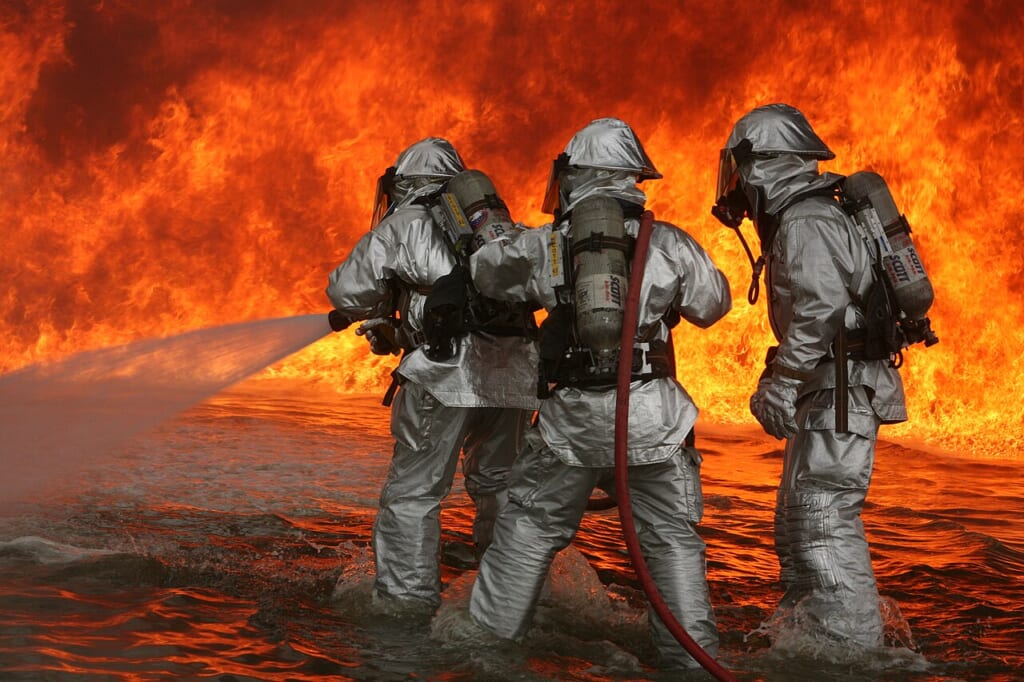 Aircraft Rescue Firefighting training | オンザショア立川店 立川駅徒歩1分年中無休の溶岩ホットヨガスタジオ 防護装備を身に着けた消防隊員たちが模擬火災の消火訓練に取り組む様子 立川駅徒歩1分年中無休の溶岩ホットヨガスタジオ
