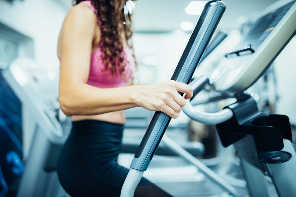 Close up of hands of a fit woman in the gym exercising legs doing cardio workout | オンザショア立川店 立川駅徒歩1分年中無休の溶岩ホットヨガスタジオ ジムで有酸素運動の器具を使って脚を動かしている女性の手元の接写 立川駅徒歩1分年中無休の溶岩ホットヨガスタジオ